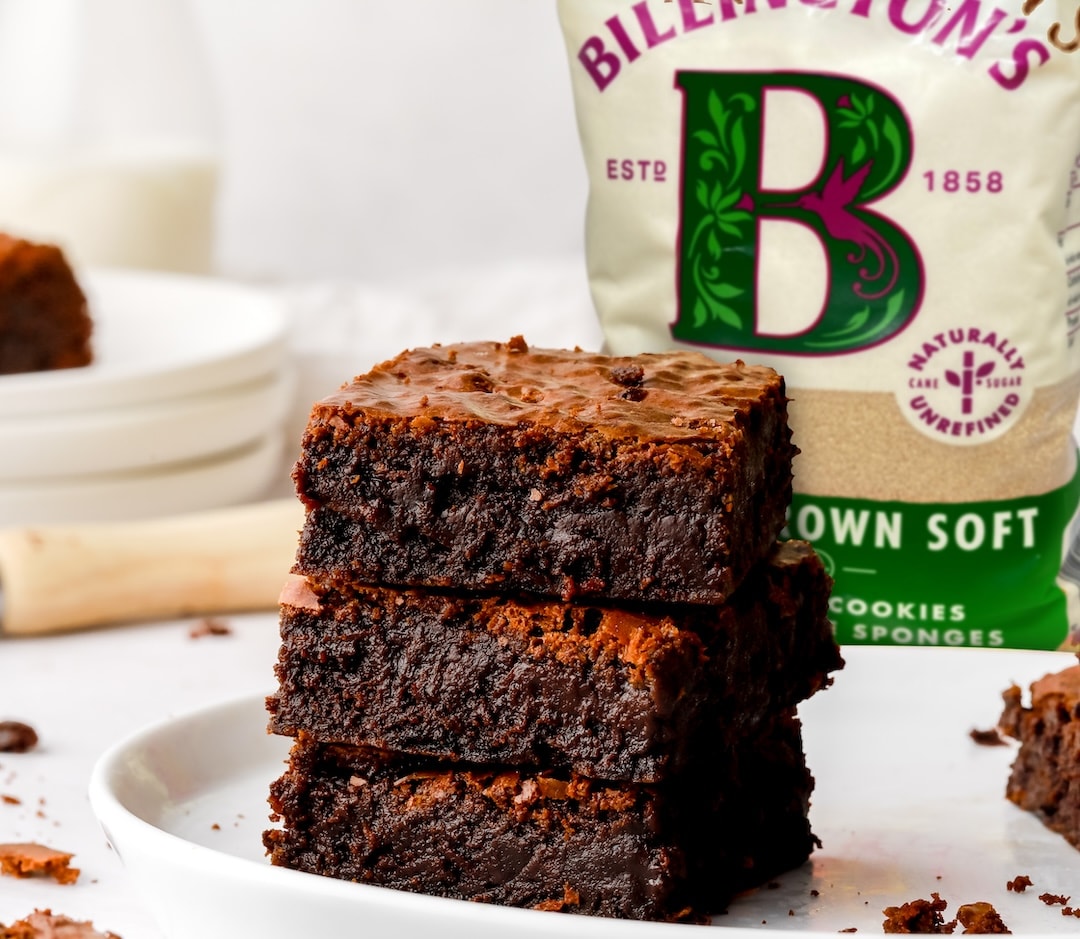 A delicious looking stack of brownies alongside a pack of Billington's Light Brown Soft sugar.